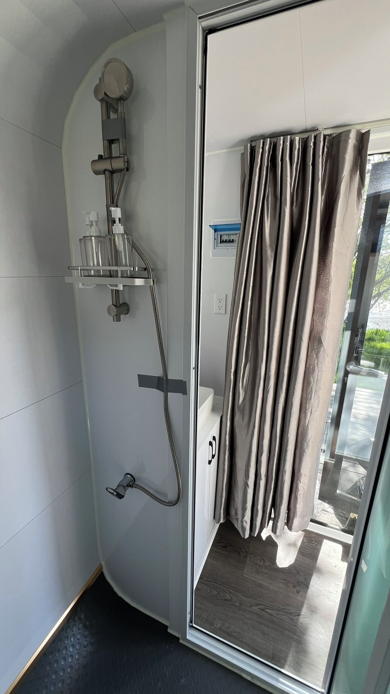 A compact bathroom with a shower, a glass door, and a curtain.