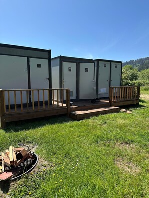 Portable portable toilets with a wooden deck in a grassy area.