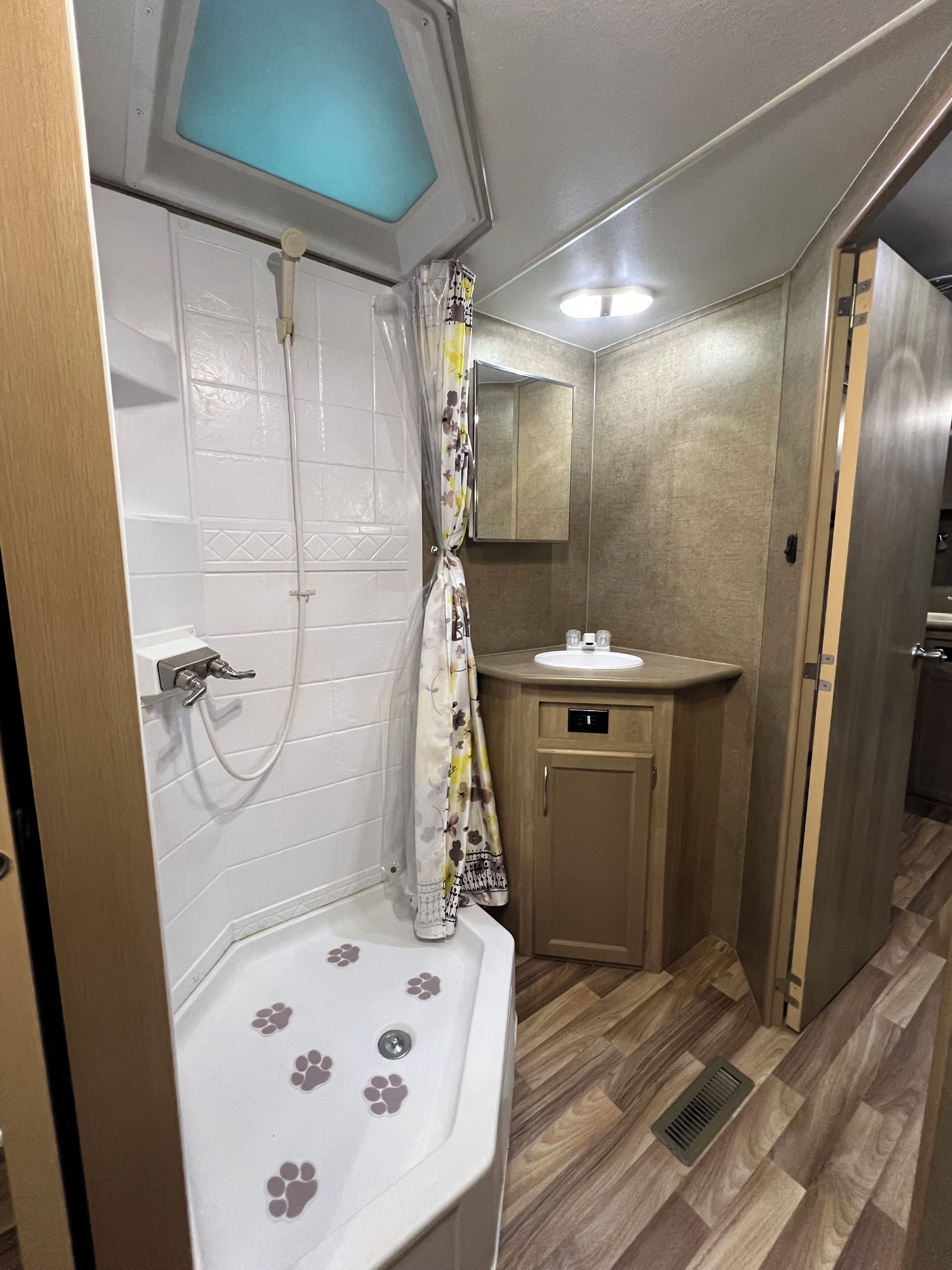 A compact bathroom with a shower, toilet, and sink.