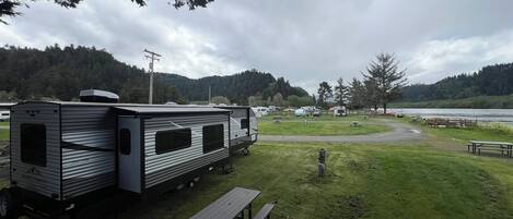 A campsite with RVs, picnic tables, and a lake view.