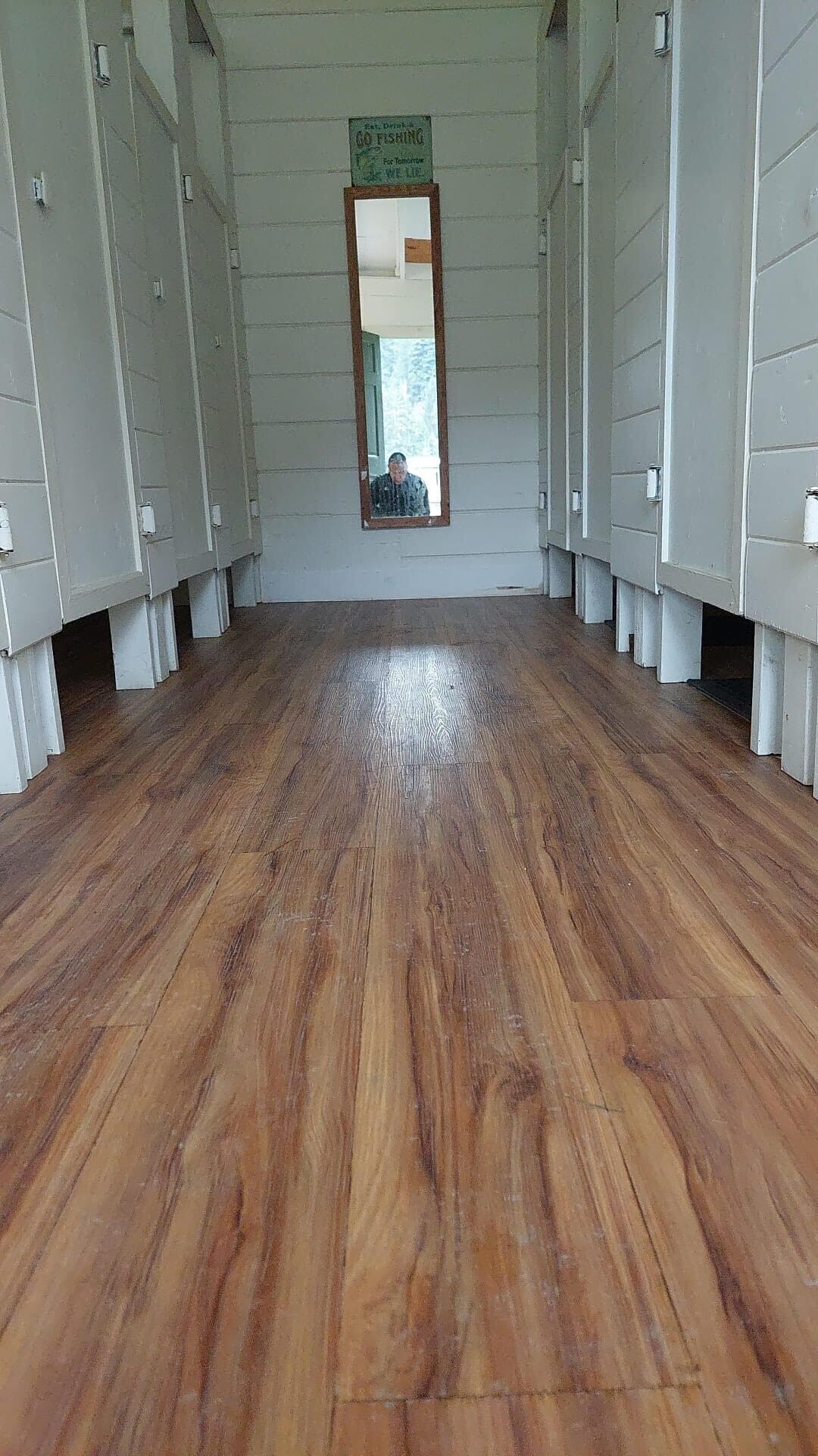 Une pièce avec un plancher en bois, des murs blancs et un miroir sur le mur du fond.