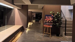 En modern inredning med en lång hall, en trappa och en affisch på ett staffli.