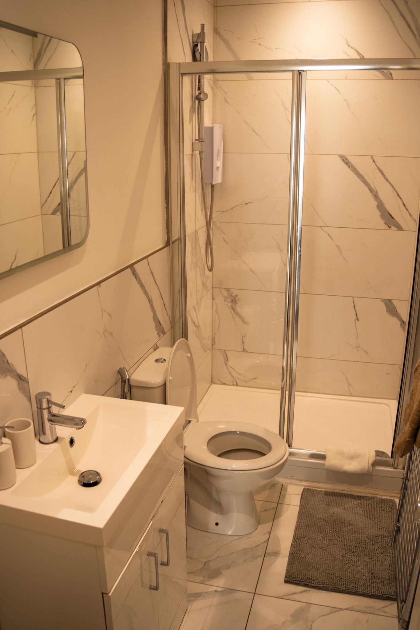 A bathroom with a shower, toilet, sink, and a mirror.