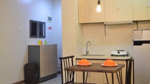 A compact kitchen with wooden cabinets, a sink, and a small dining area with two chairs and a table.