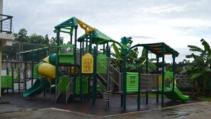 A playground with green and yellow play structures, including slides and climbing areas.