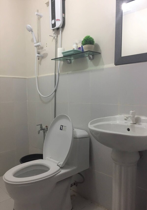 A bathroom with a toilet, a sink, and a shower unit.