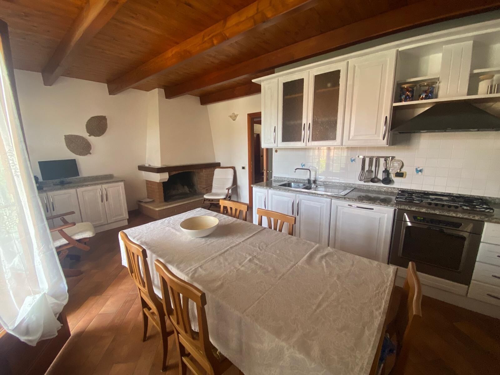 Une cuisine avec des meubles blancs, un four encastré et une table à manger avec des chaises.