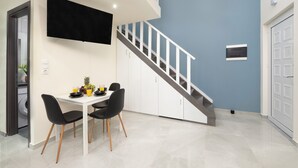 A modern kitchen with a dining area, a staircase, and a flat-screen TV mounted on the wall. - Golden sand 3 (Ialisos)