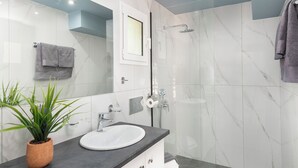A modern bathroom with a white sink, a built-in washing machine, a shower, and a towel rack. - Golden sand 3 (Ialisos)