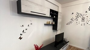 A modern living room with a black entertainment unit, a flat-screen TV, and decorative wall decals. - The Window on Assisi (Bastia Umbra)