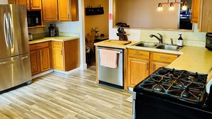 A modern kitchen with wooden cabinets, stainless steel appliances, and a central island with a sink. - Charming home on the lake! (Macy)