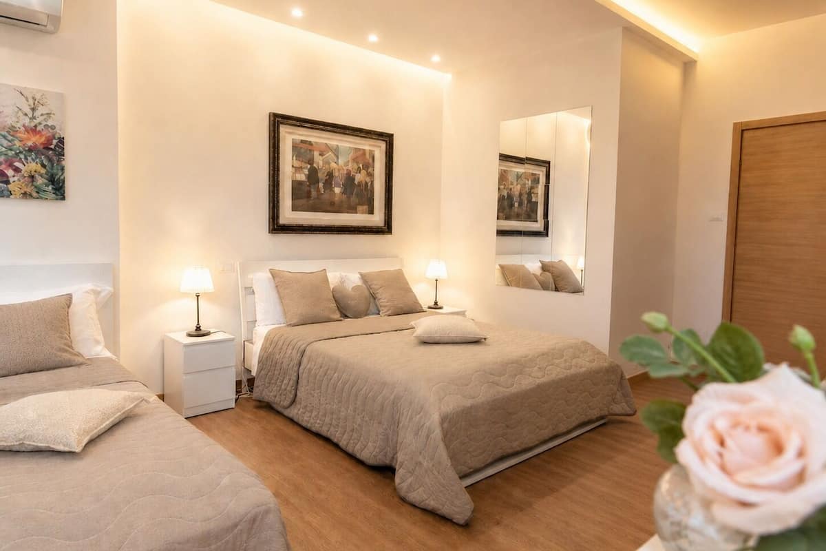 A hotel room with a large bed, bedside tables, a mirror, and a picture on the wall.