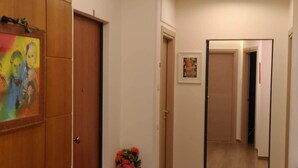 A hallway with wooden doors, a painting, and a vase of flowers. - Central Domus (Matera)
