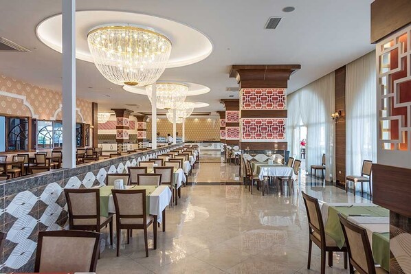 A spacious dining area with multiple tables and chairs, large chandeliers, and patterned wall designs. - Simurg Luxury Halal Hotel (Alanya)