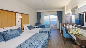 A hotel room with two beds, a desk, a TV, and a balcony with a view of the sea. - Simurg Luxury Halal Hotel (Alanya)