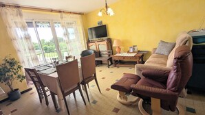 Un salon comprenant une table à manger, des chaises, un canapé, un téléviseur et une plante en pot.
