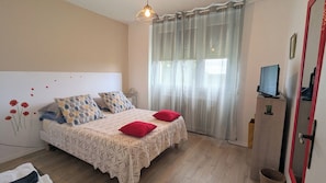 A bedroom with a bed, two pillows, a TV, and a window with curtains. - Detached house 25 minutes from the center of Albi. (Saint-Jean-de-Marcel)