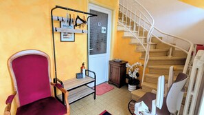 A room with a red chair, a wooden table, a metal rack with toiletries, a staircase, and a door with a 'WiFi' sign. - Detached house 25 minutes from the center of Albi. (Saint-Jean-de-Marcel)