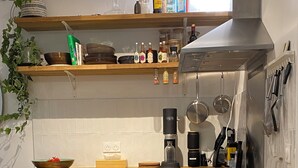 A modern kitchen with wooden countertops, a coffee maker, and a variety of bottles on the shelves.