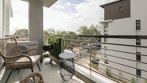 Ein Balkon mit Korbstühlen, einem runden Tisch und einer Samsung-Klimaanlage.