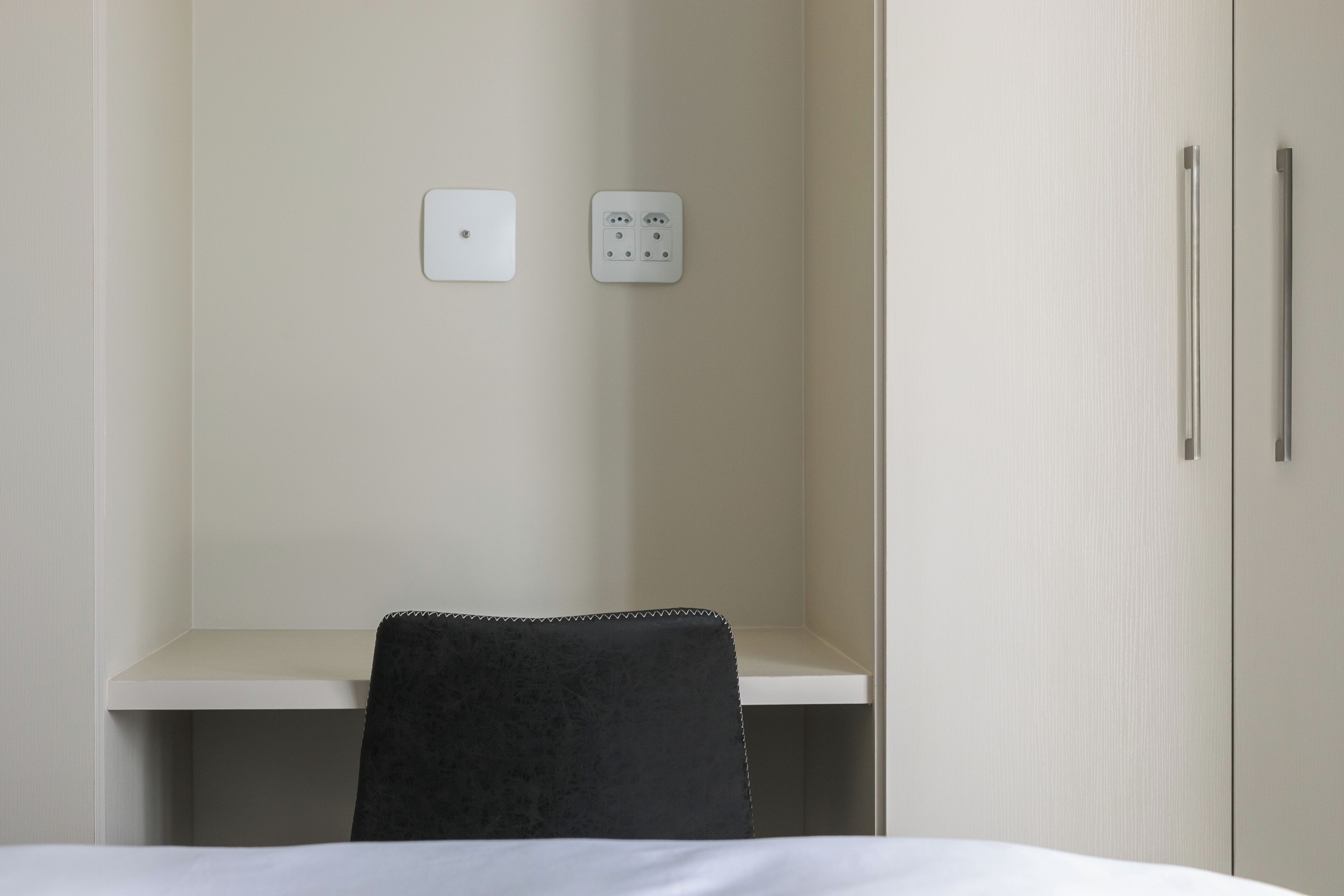 Ein Hotelzimmer mit Bett, Schreibtisch, Stuhl und Kleiderschrank.