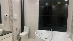 A modern bathroom with a bathtub, toilet, and vanity. - Adams Hotel (Yerevan)