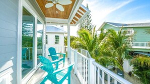 A covered outdoor area with a ceiling fan, a table, and two chairs. - Surfer's Dream- 4 bedroom close to beach, pool and spa with rooftop (Holmes Beach)