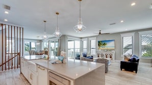 A spacious kitchen with a large island, pendant lights, and a view of the outdoors.