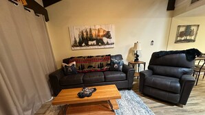 A living room with a dark leather sofa, a wooden coffee table, and a rug. - Charming 1-bedroom, one-loft condo in beautiful Sevierville, with pool and WiFi. (Sevierville)