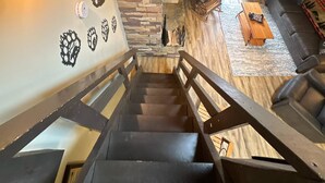 A staircase leading to a living area with a stone wall, a wooden floor, and a sofa. - Charming 1-bedroom, one-loft condo in beautiful Sevierville, with pool and WiFi. (Sevierville)