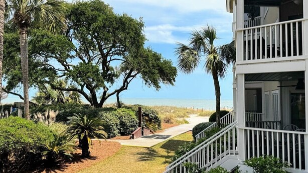 Una proprietà fronte spiaggia con una terrazza in legno, palme e vista sull'oceano.
