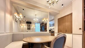 A dining area with a round table, cushioned bench seating, and a chandelier. - Merveil - Signature Suite - Tour Eiffel - Bourgogne (Paris)