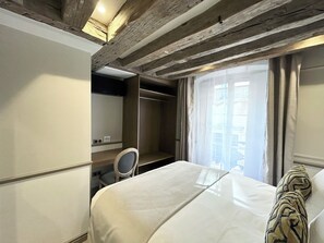 Una habitación de hotel con cama, escritorio, silla y armario.