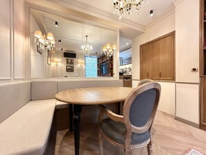 A dining area with a round table, cushioned bench seating, and a chandelier. - Merveil - Signature Suite - Tour Eiffel - Bourgogne (Paris)