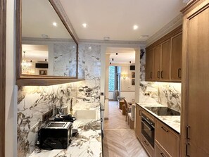A modern kitchen with marble countertops, wooden cabinets, and a Bosch toaster.