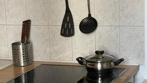 A kitchen with a built-in induction cooktop, a stainless steel pot on it, and a white oven below.