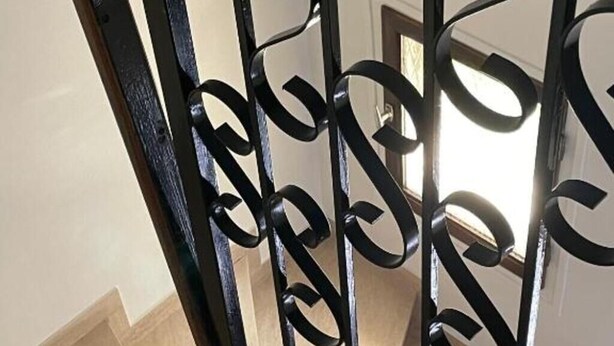 A staircase with a black metal railing featuring a decorative design.