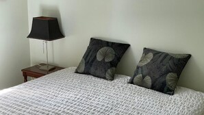 A bed with a white textured bedspread and two decorative pillows with a circular pattern.
