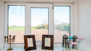 A window with two framed pictures, a brass candelabra, and a coffee maker on a shelf. - 6 Person Holiday Home in Skaerbaek (Skaerbaek)