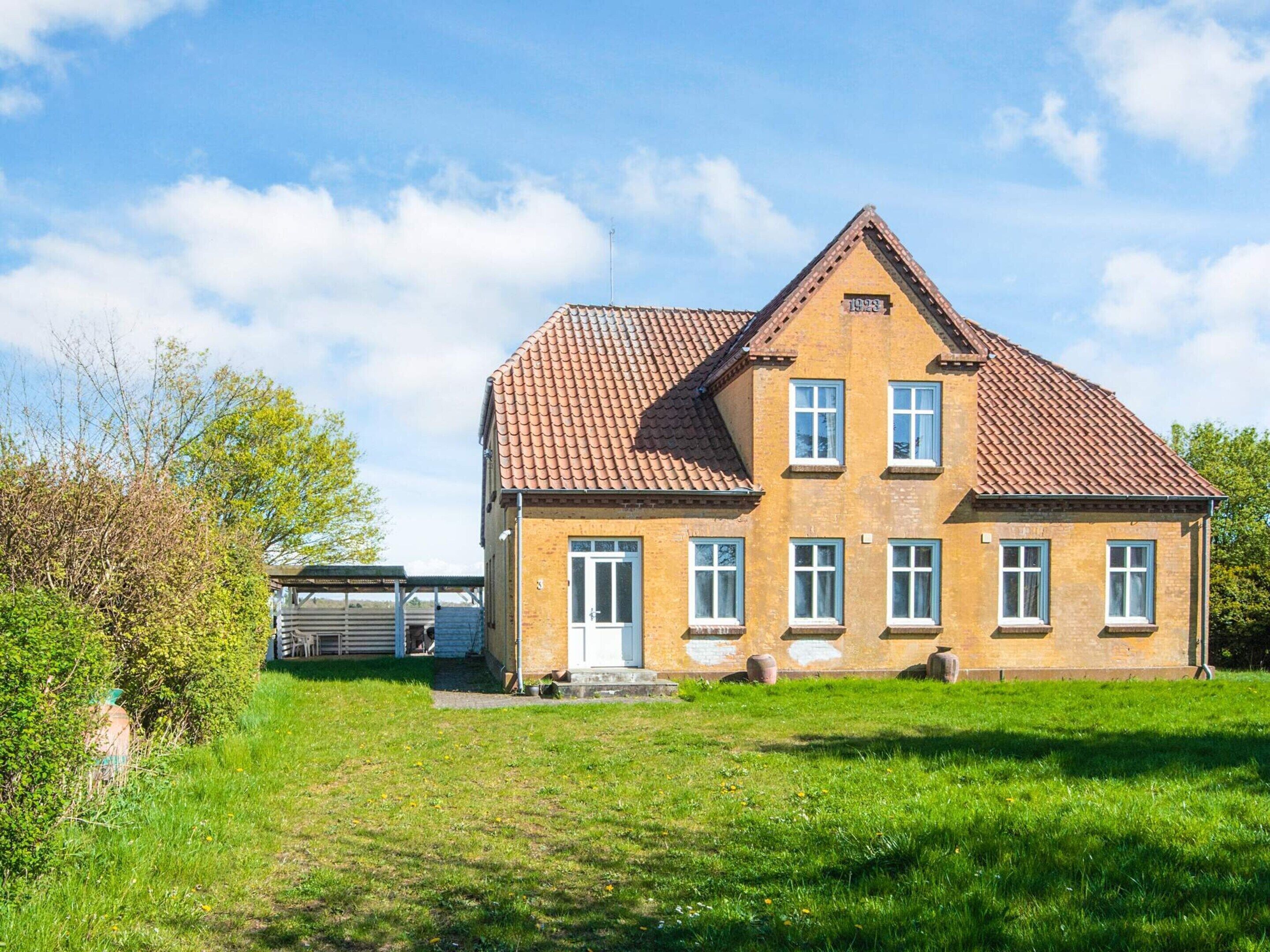 A two-story house with a tiled roof, a front door, and a small porch.