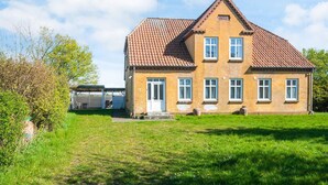 A two-story house with a tiled roof, a front door, and a small porch. - 6 Person Holiday Home in Skaerbaek (Skaerbaek)