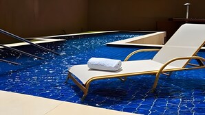 En pool på taget med to liggestole, hvoraf den ene har et håndklæde, og en poolstige.