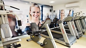 Et fitnesscenter med løbebånd, træningsmaskiner og et stort spejl.