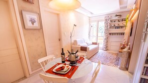 A dining area with a round table, chairs, a wine bottle, and a hot pot. - Apto no Coração do Capivari e Perto de Tudo! (Campos do Jordão)