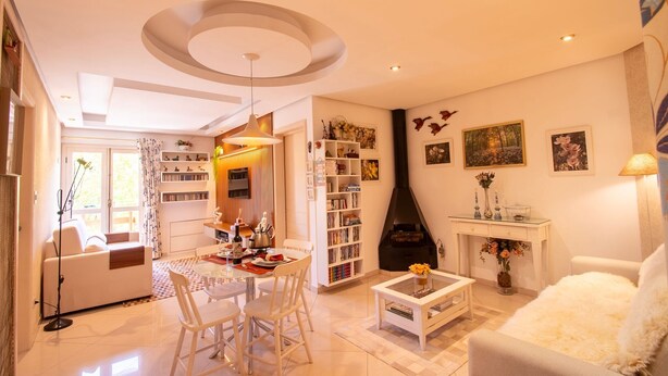 A modern living room with a fireplace, a dining area, and a bookshelf. - Apto no Coração do Capivari e Perto de Tudo! (Campos do Jordão)