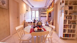 A dining area with a round table, chairs, a wine bottle, and a hot plate. - Apto no Coração do Capivari e Perto de Tudo! (Campos do Jordão)