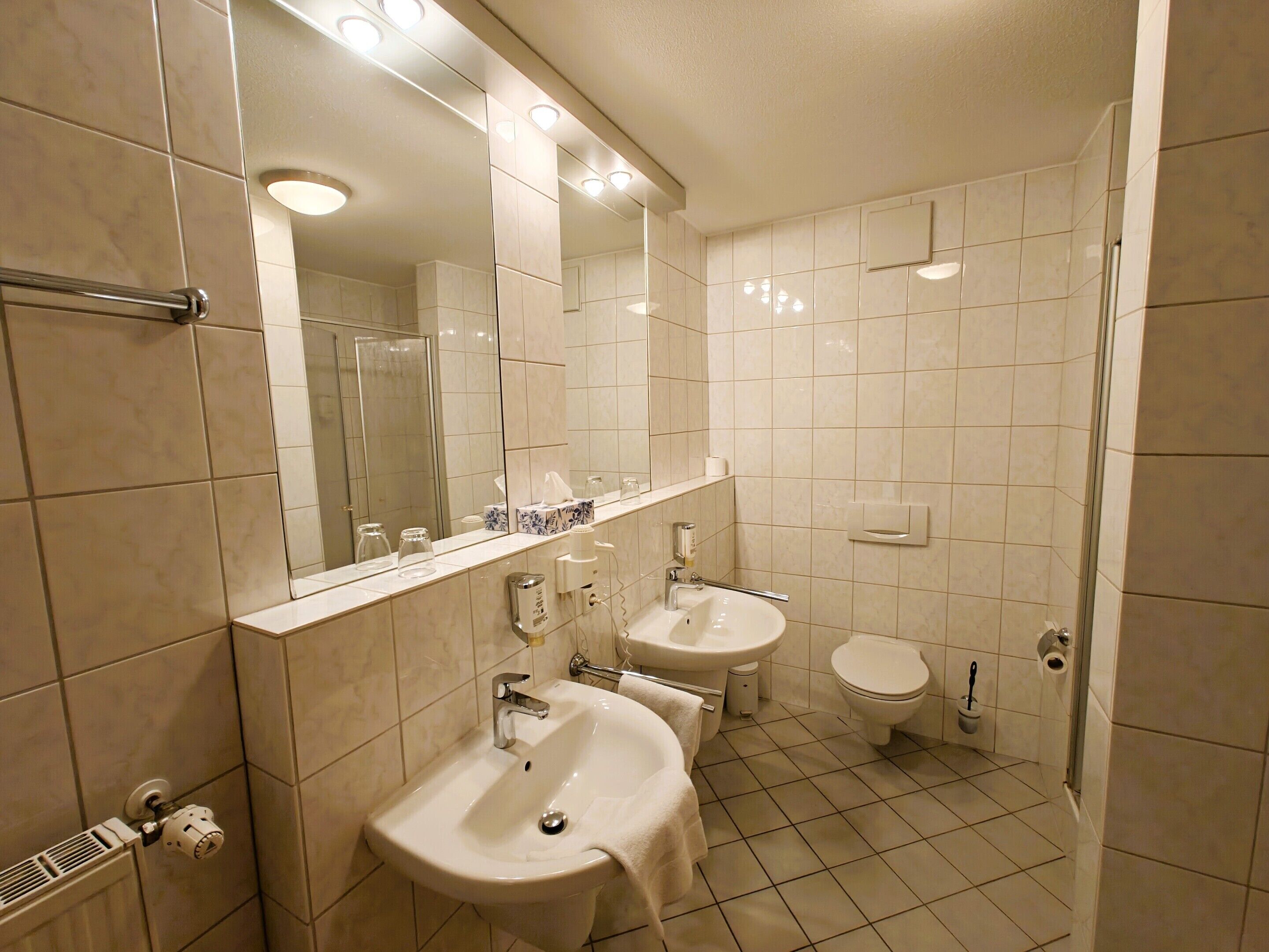 Un baño moderno con dos lavamanos, inodoro y ducha.
