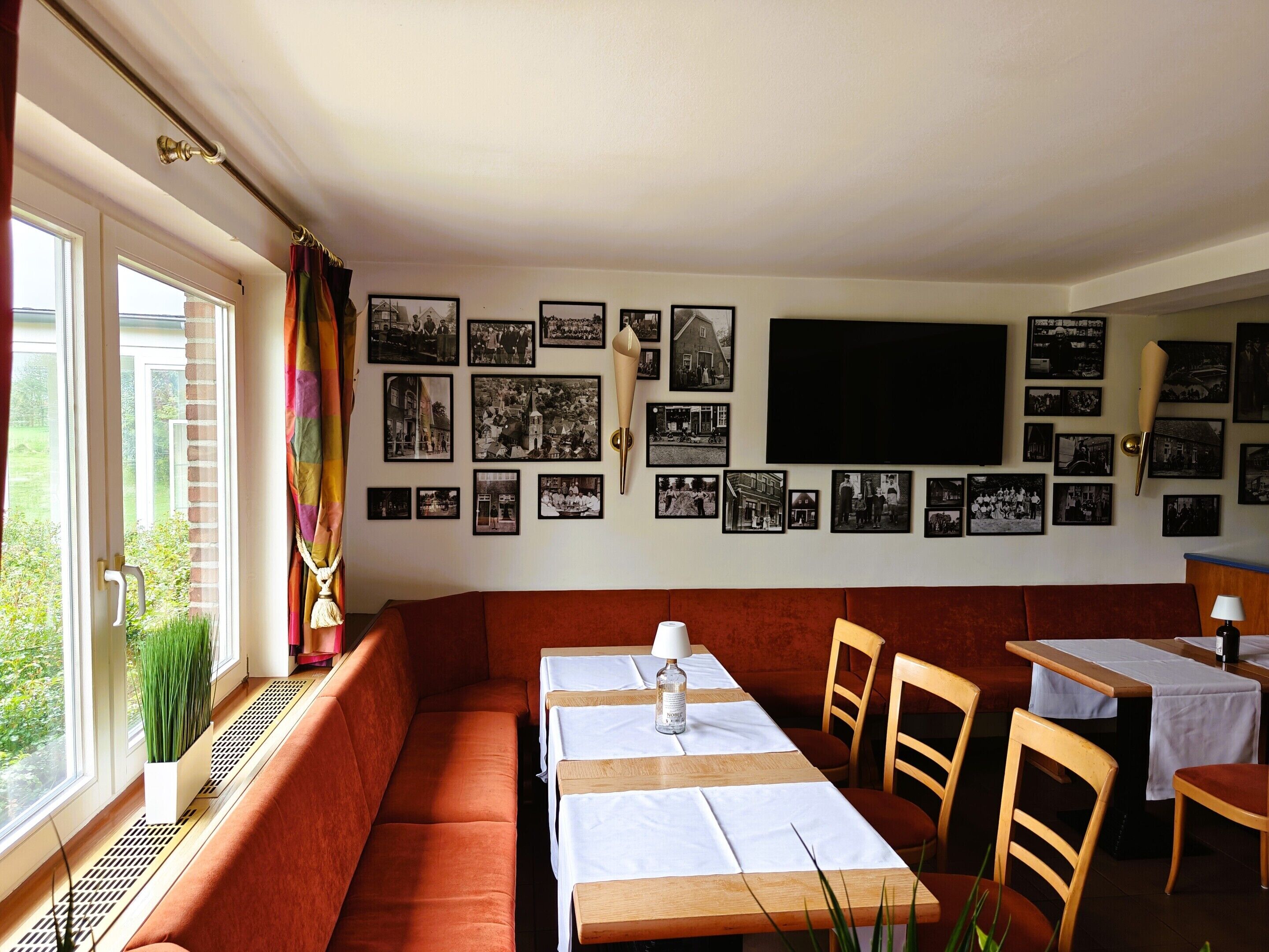 A cozy dining area with a long table, cushioned seating, and a wall adorned with black and white photographs.