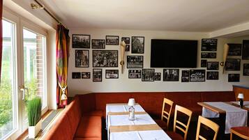 Un comedor acogedor con una mesa larga, asientos acolchados y una pared decorada con fotografías blanco y negro.