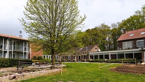 Et boligområde med huse, et træ og en have bag en hegn.